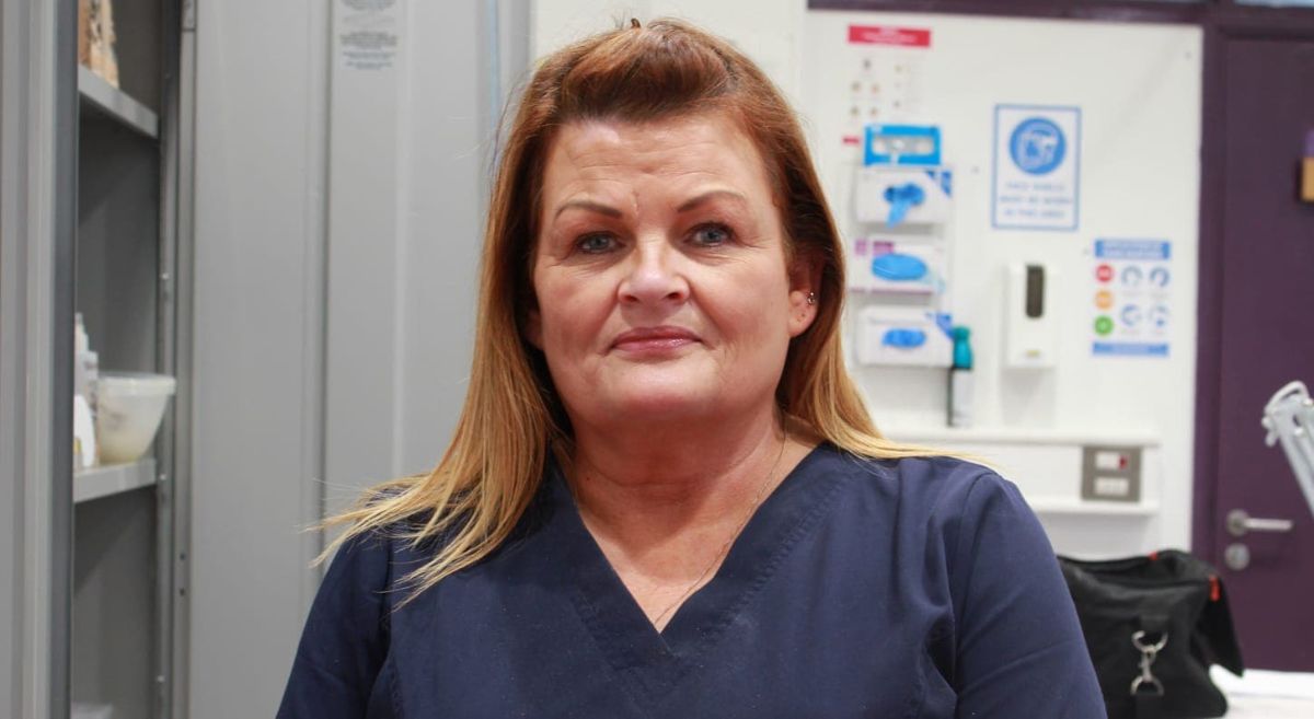 Woman with brown and blonde coloured hair and wearing a blue top smiling at the camera.